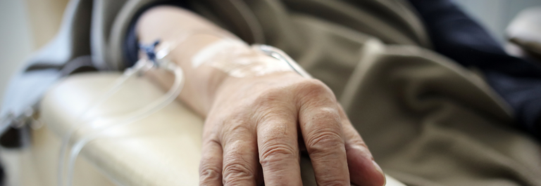 Patient's arm resting on a chair with an iv inserted.