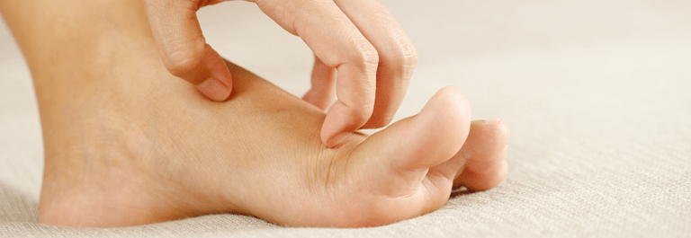 Fingers scratching the top of a bare foot.