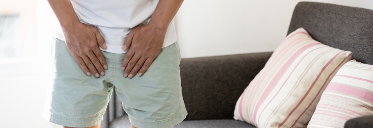 man wearing shorts and holding hands over groin chafing