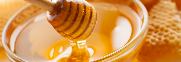 close up picture of honey and honey ladle