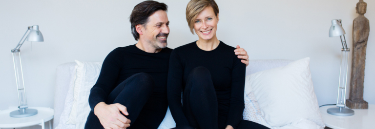 man and woman sitting on bed wearing Remedywear shirt and pants for adults in black