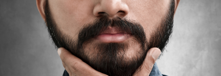 close up shot of man cupping his chin with focus on his beard