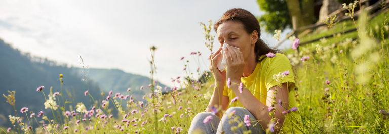 woman sitting in grass blowing nose