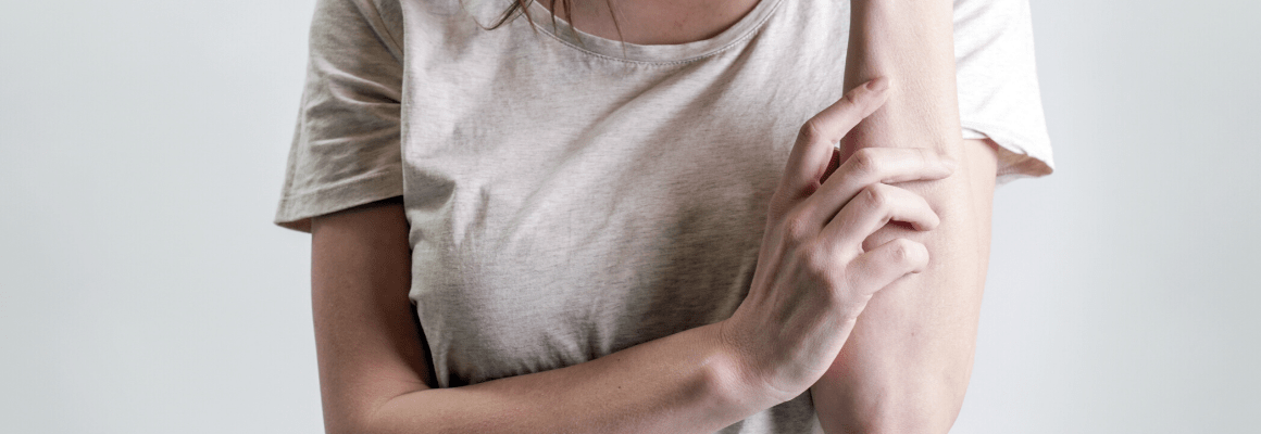 Best Clothing for Psoriasis - Woman scratching arm