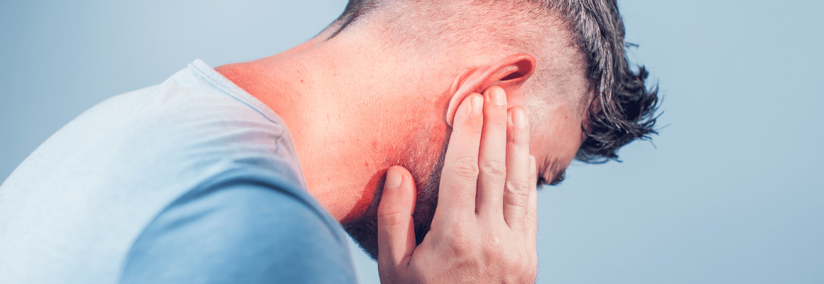 ear eczema - man in blue short holding ear in pain