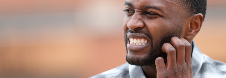 man grimacing and scratching itchy beard