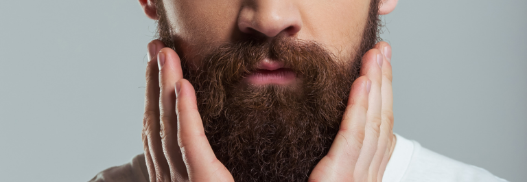 man cupping face and holding beard 