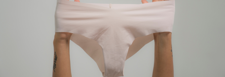 two arms holding up a pair of beige underwear