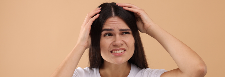 woman grimacing as she touches head of scalp psoriasis