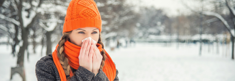 Woman blowing her nose into a tissue in cold weather