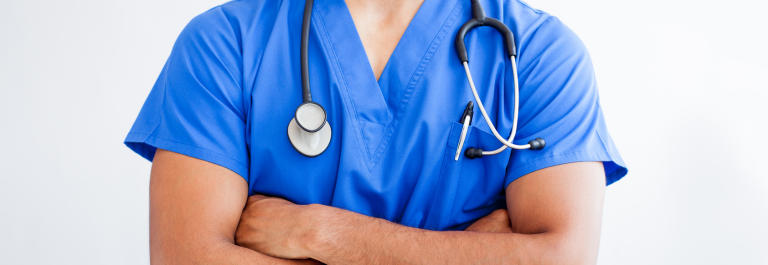 man wearing scrubs crossing his arms