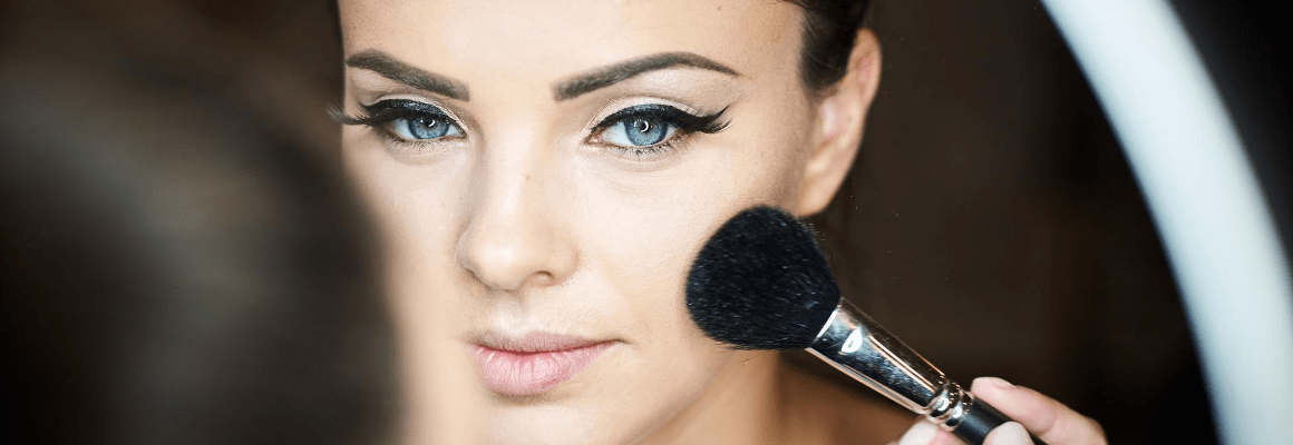 Makeup and Eczema - woman putting on makeup in mirror