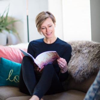 Woman reading a book on a couch in a cozy living room.